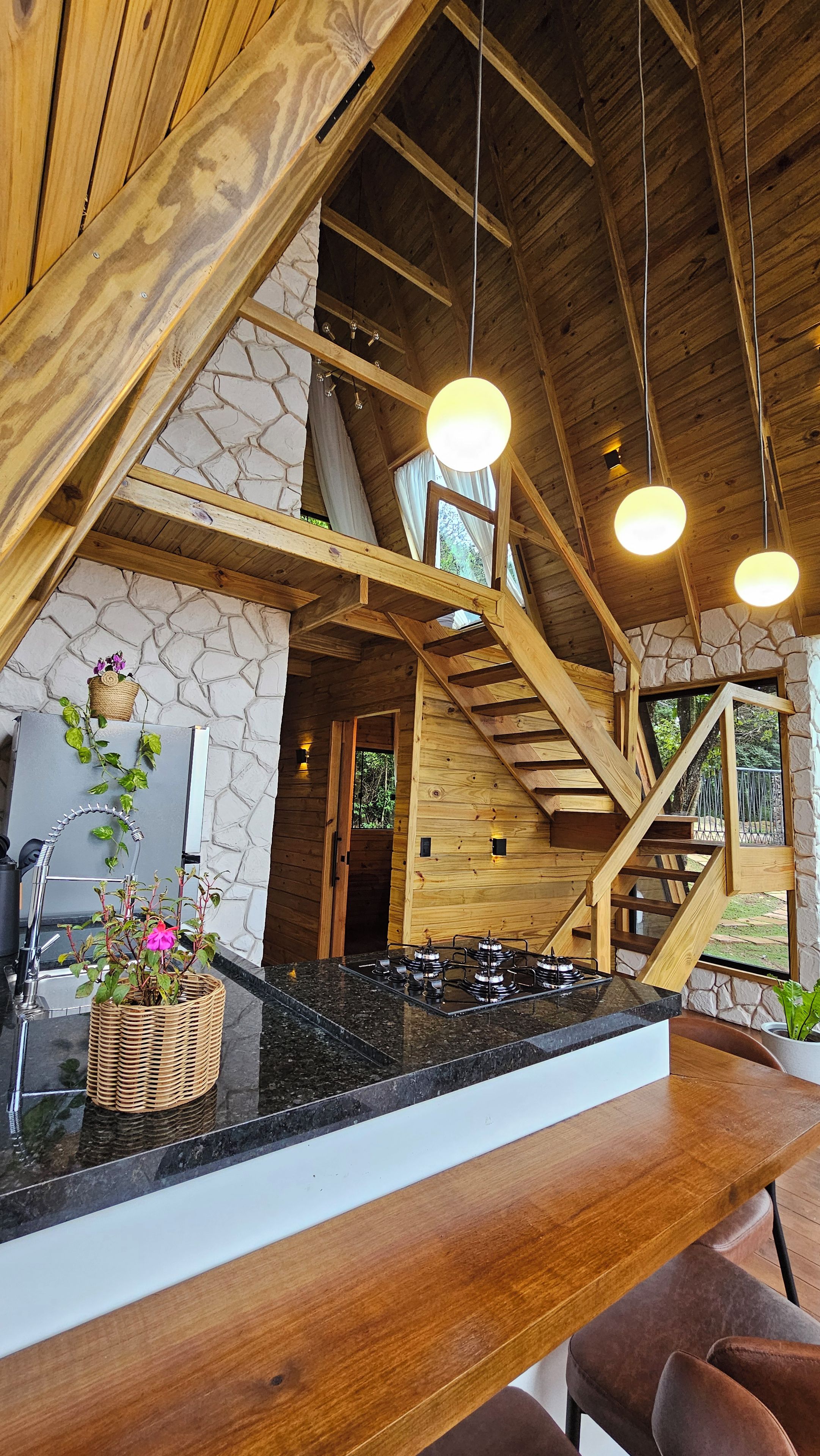 A wooden interior with a kitchen area, a dining table, and a staircase.