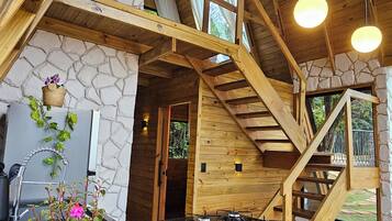 A wooden interior with a kitchen area, a dining table, and a staircase.