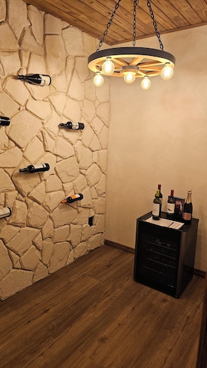 A room with a stone wall, wooden ceiling, and a wine rack with bottles.