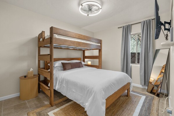 Ein Etagenbett mit Holzrahmen, ein Nachttisch mit Lampe und ein Spiegel an der Wand.