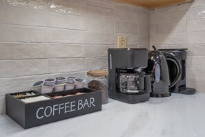 Ein Kaffee-Bereich mit einer Kaffeemaschine, Tassen und einem Behälter mit der Aufschrift 'COFFEE BAR'.