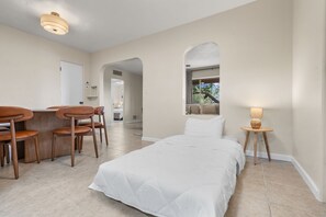 Une chambre d’hôtel avec un lit, un bureau avec des chaises, une lampe et une vue sur l’extérieur.