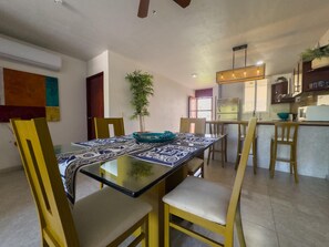 A dining area with a glass table, wooden chairs, and a patterned tablecloth. - Sunsets & Serenity at Playa Escondida | 2BR Beachfront Getaway (Mazatlan)