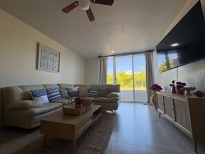 A living room with a sofa, coffee table, and a TV mounted on the wall. - Sunsets & Serenity at Playa Escondida | 2BR Beachfront Getaway (Mazatlan)