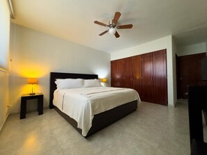 Ein Schlafzimmer mit einem Bett, Nachttischen, einem Deckenventilator und Holzschränken.