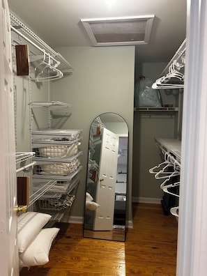 Un vestidor amplio con varias estanterías y un espejo de cuerpo entero.