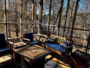 Interior acogedor de una cabaña con terraza de madera, un sofá, sillas y una mesa.