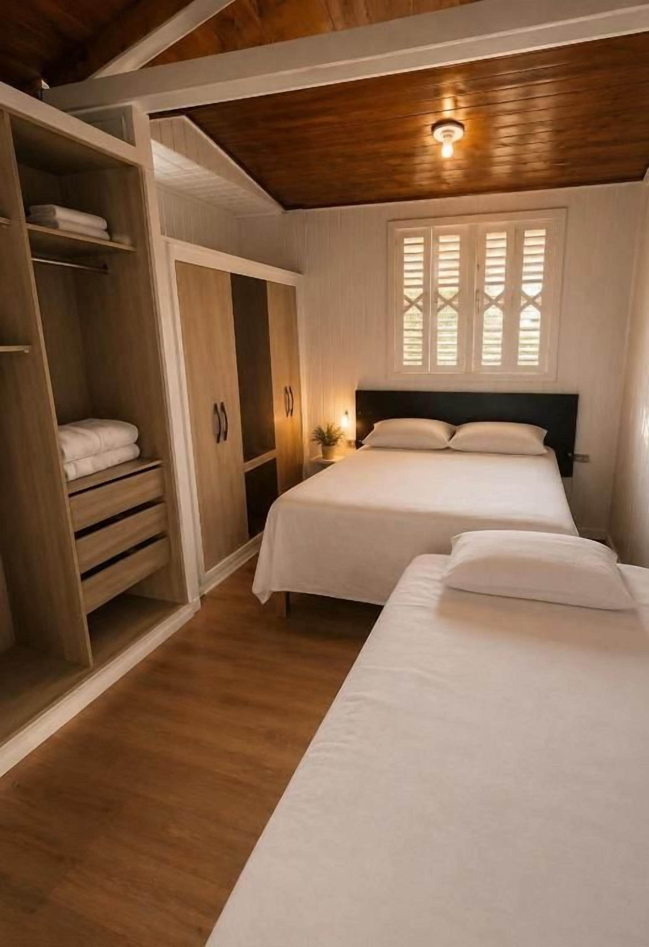Un dormitorio con cama doble, un armario y una ventana con contraventanas.