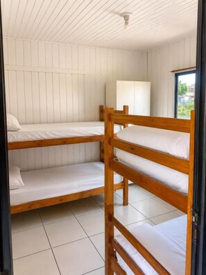 A room with bunk beds, a window, and a white wall.
