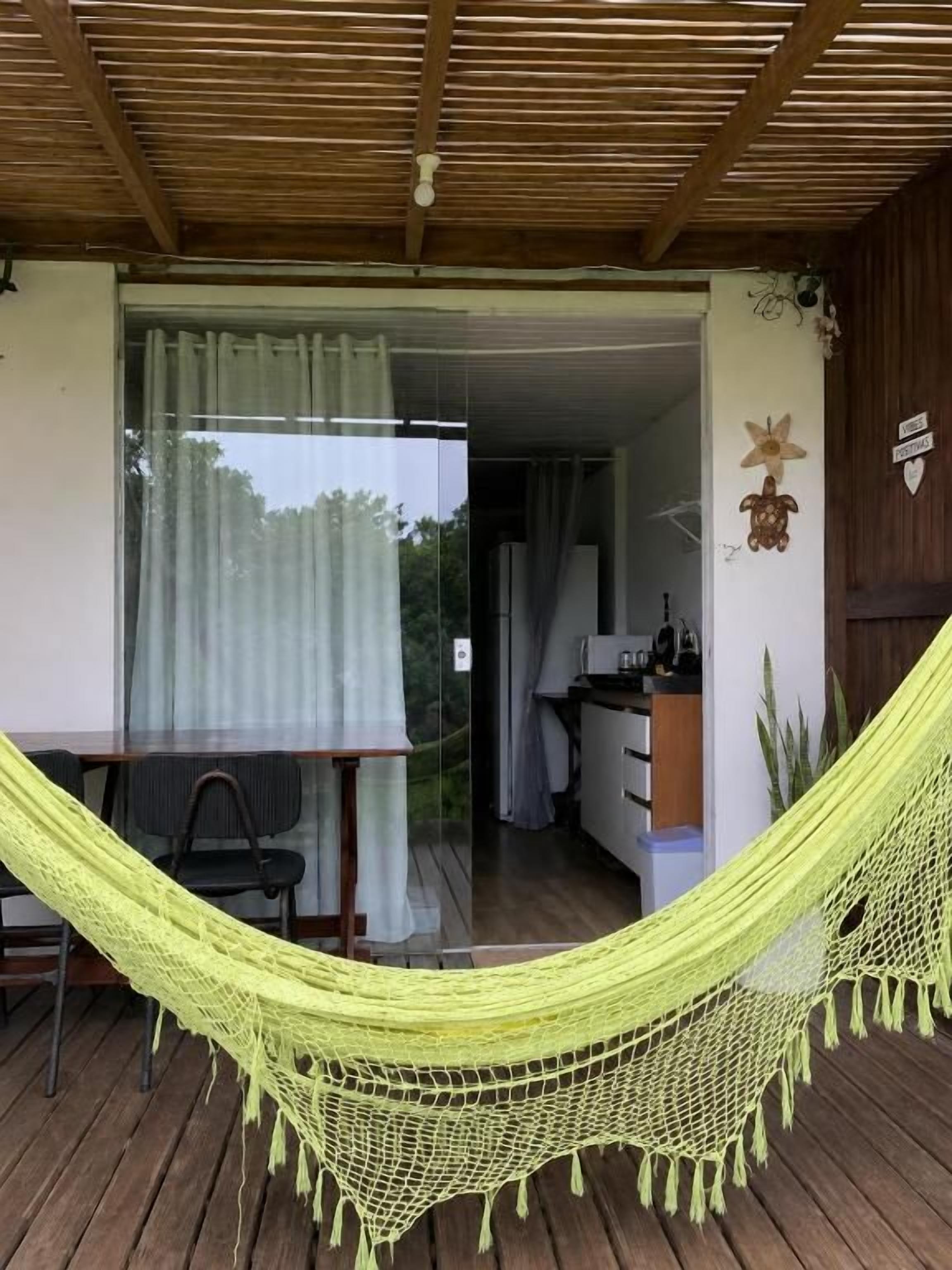 Una hamaca sobre una terraza de madera con vista a un espacio interior.