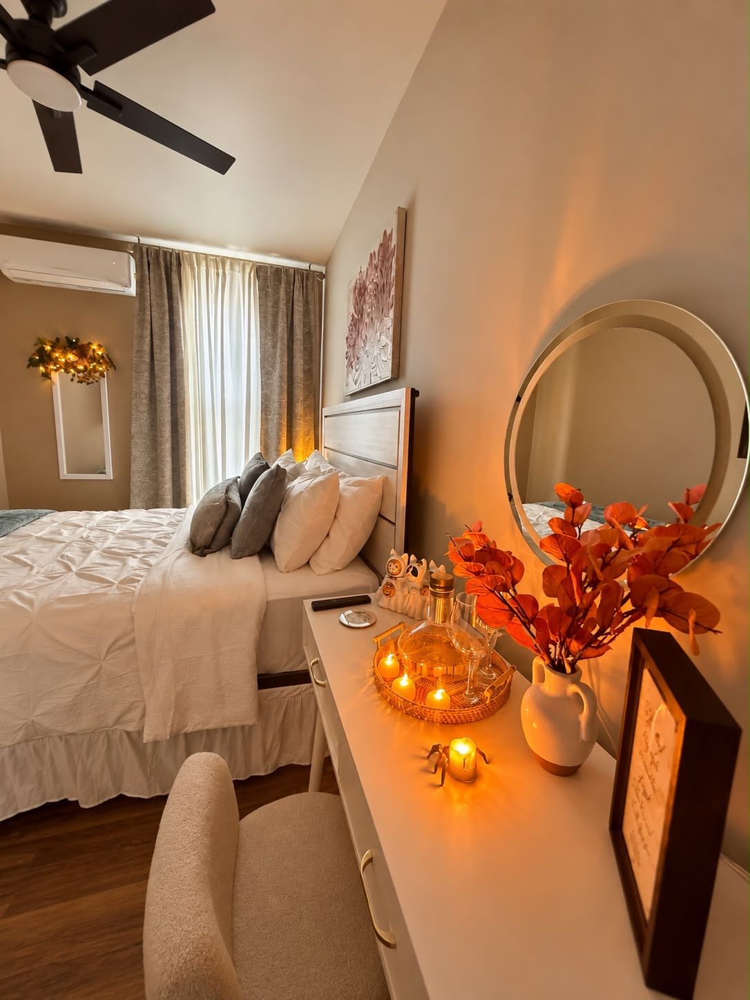 A bedroom with a bed, bedside table, mirror, and a ceiling fan.
