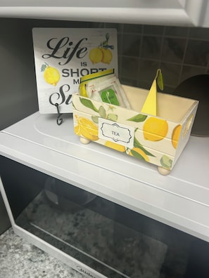 A kitchen counter with a decorative sign and a tea box. - Cozy 2-Bedroom • 10 Min to JFK • 5 Min to Casino (Ozone park)