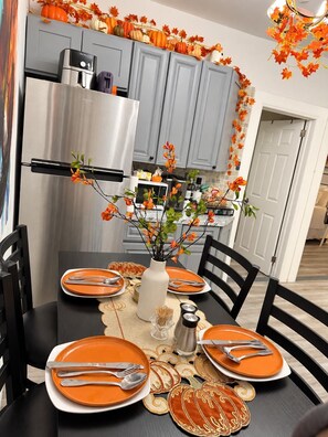 Ein Esstisch mit orangefarbenen Tellern, Besteck und einer Vase mit orangefarbenen Blumen.