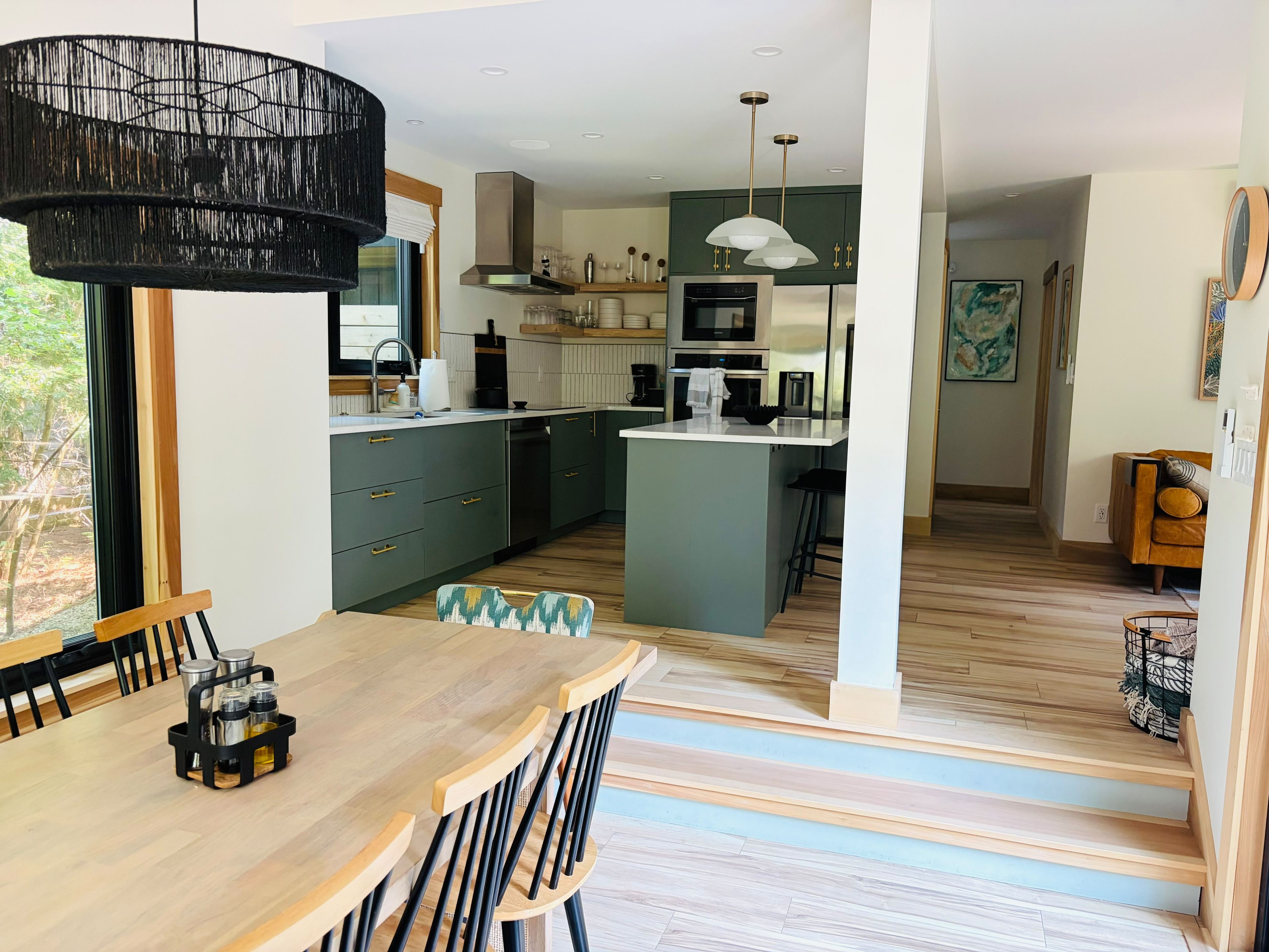 A modern kitchen with a central island, wooden dining table, and chairs.
