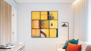 Uma sala de estar moderna com um sofá, uma mesa de centro com uma tigela, uma obra de arte na parede e um abajur.