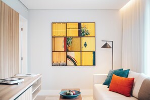 A modern living room with a sofa, a coffee table with a bowl, a wall art piece, and a floor lamp. - 752 Ocean Ave  Unit A & B (Wells)