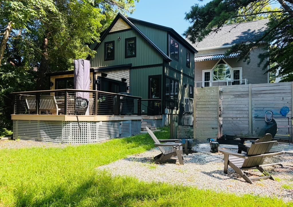 Une maison à deux étages dotée d’une terrasse, d’un espace salon extérieur et d’une zone délimitée par une clôture.
