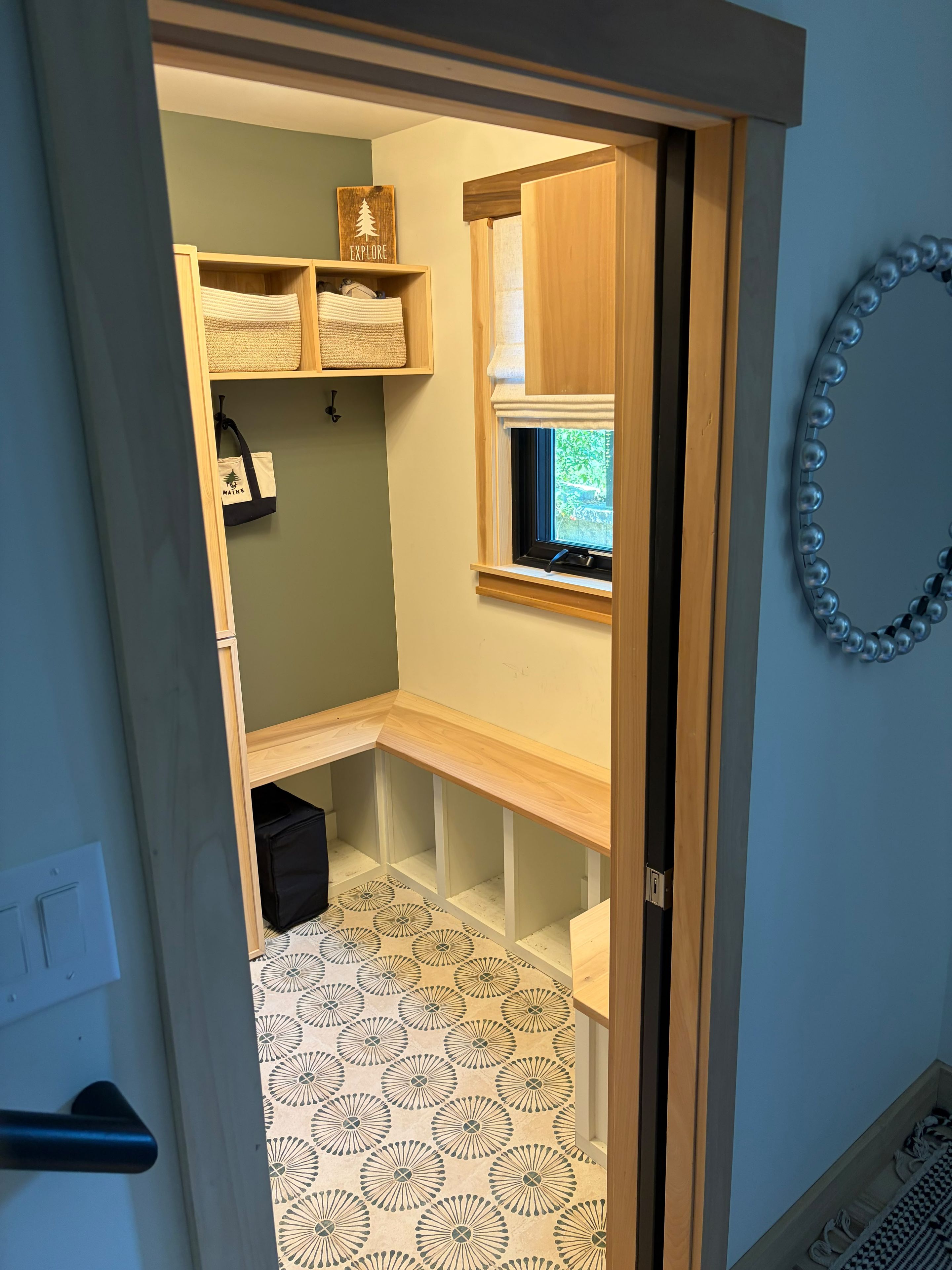 A small, narrow room with a window, a shelf with a 'Explore' sign, and a patterned floor.