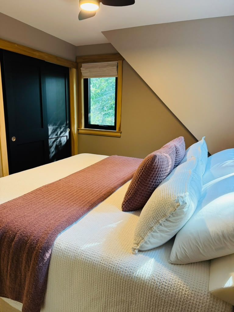 A bedroom with a bed, a window, and a door.