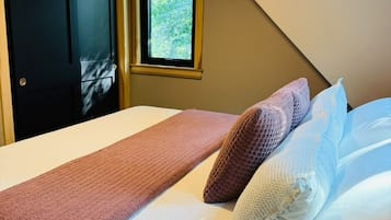 A bedroom with a bed, a window, and a door.