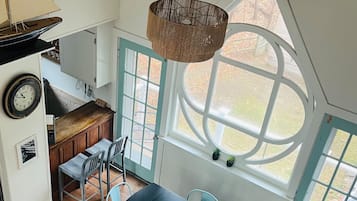 A dining area with a table, chairs, and a hanging light fixture.
