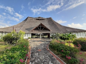 A traditional thatched-roof building with a stone pathway leading to a covered entrance. - The One Watamu Bay (Watamu)