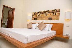 A bed with a wooden headboard, white bedding, and two wall-mounted lamps. - The One Watamu Bay (Watamu)