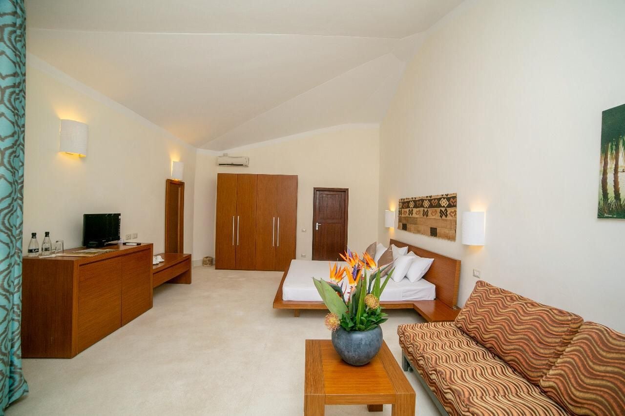 A compact hotel room with a bed, a sofa, a wooden desk, and a TV.