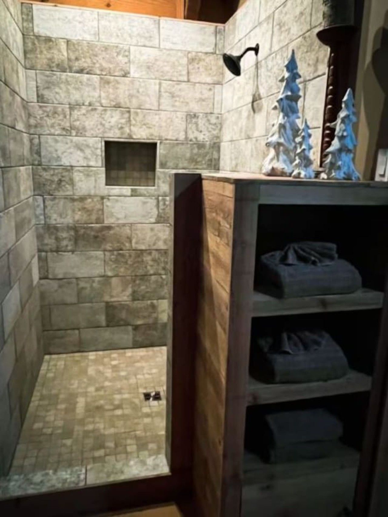 A bathroom with stone walls, a shower area, and a wooden shelf with towels.