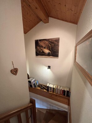 A staircase with a wooden handrail, a wall-mounted picture of a bear, and a collection of books on a shelf. - Chalet, 200m from ski lifts, balcony, fireplace or stove, tv, ski locker, 98m², Peisey-Vallandry (Landry)