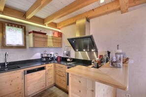A modern kitchen with wooden cabinetry, a stainless steel range hood, and a built-in dishwasher. - Chalet, 200m from ski lifts, balcony, fireplace or stove, tv, ski locker, 98m², Peisey-Vallandry (Landry)