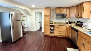A modern kitchen with stainless steel appliances, wooden cabinets, and a granite countertop.