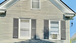A two-story house with a covered porch, a black front door, and a bench. - More, than just a place to sleep - welcome home! (Cambridge)