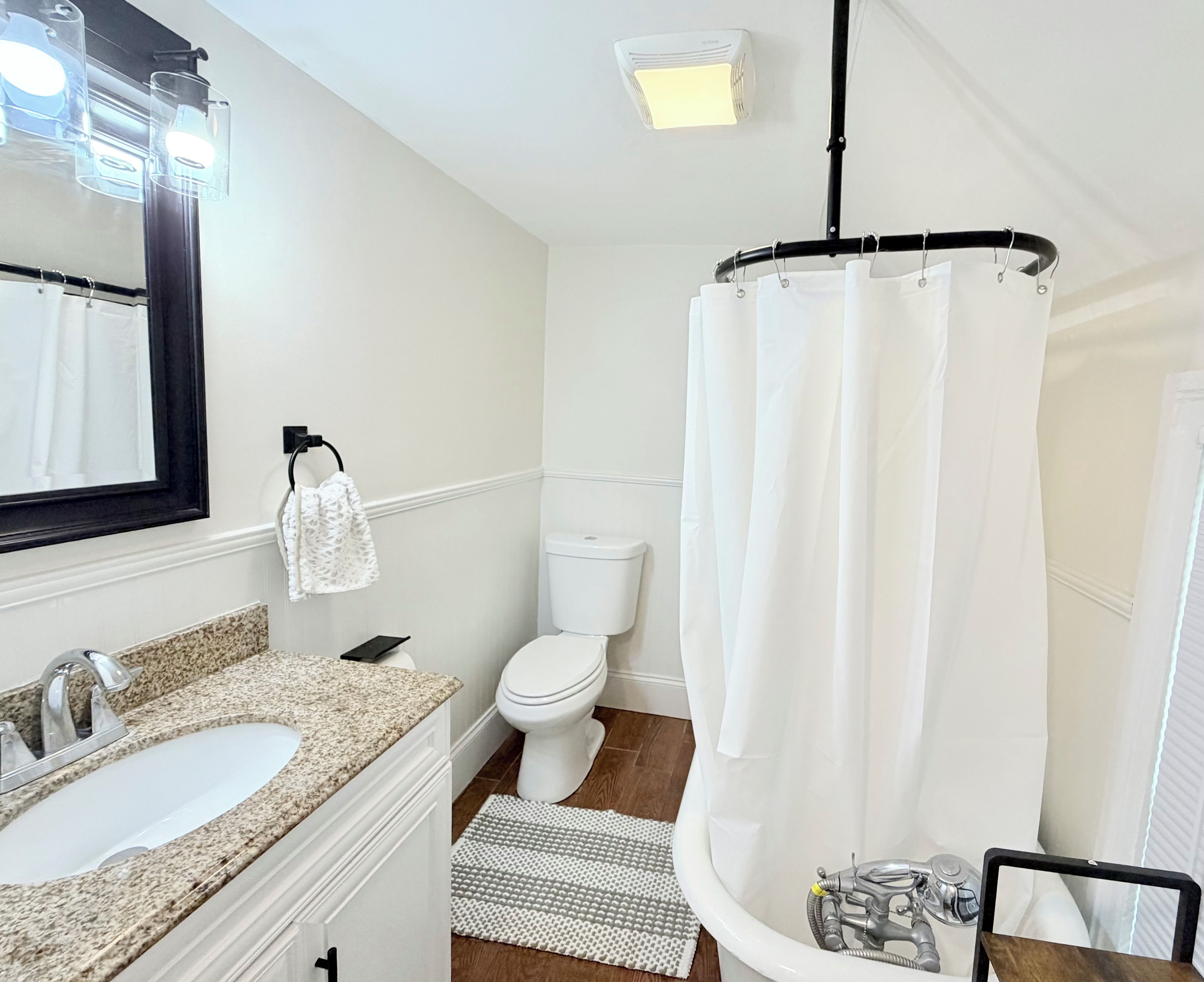 Une salle de bain avec un lavabo blanc, des toilettes et un rideau de douche.