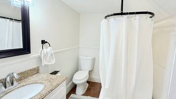Une salle de bain avec un lavabo blanc, des toilettes et un rideau de douche.