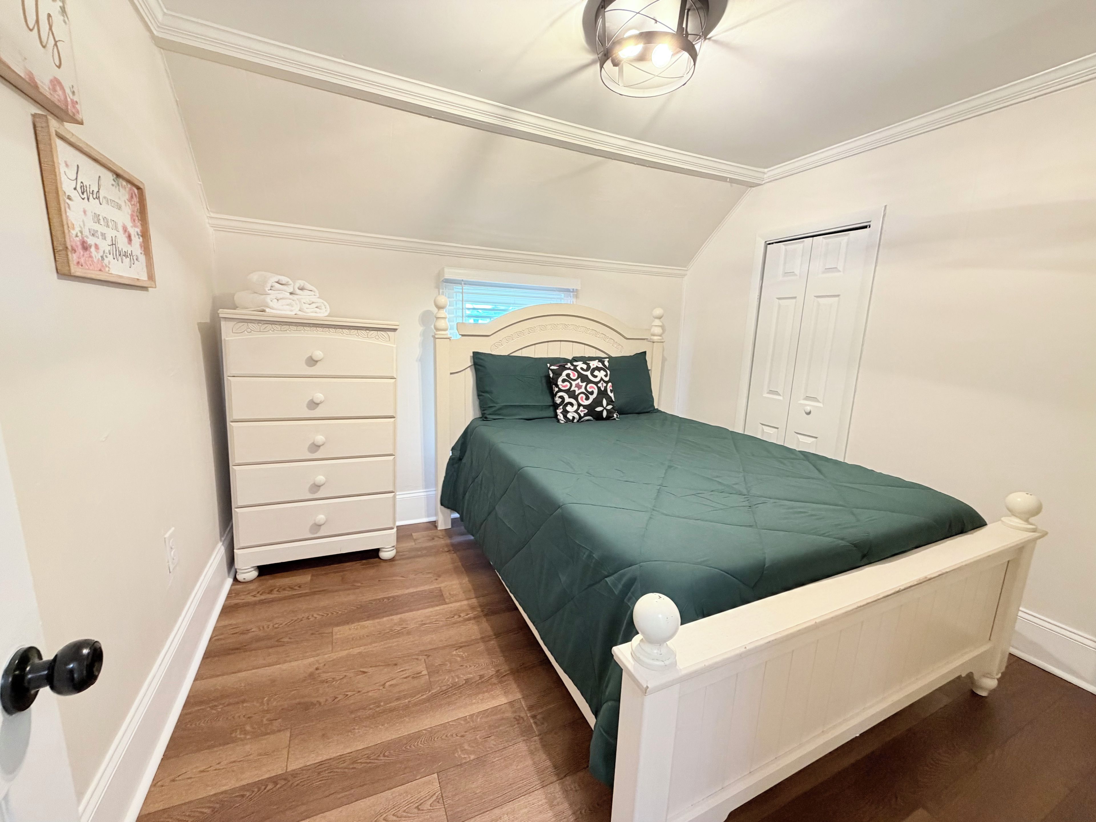 Une chambre à coucher avec un lit, une commode et une porte.