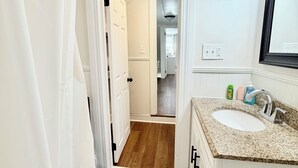 A bathroom with a white bathtub, a sink with a granite countertop, and a shower curtain. - More, than just a place to sleep - welcome home! (Cambridge)