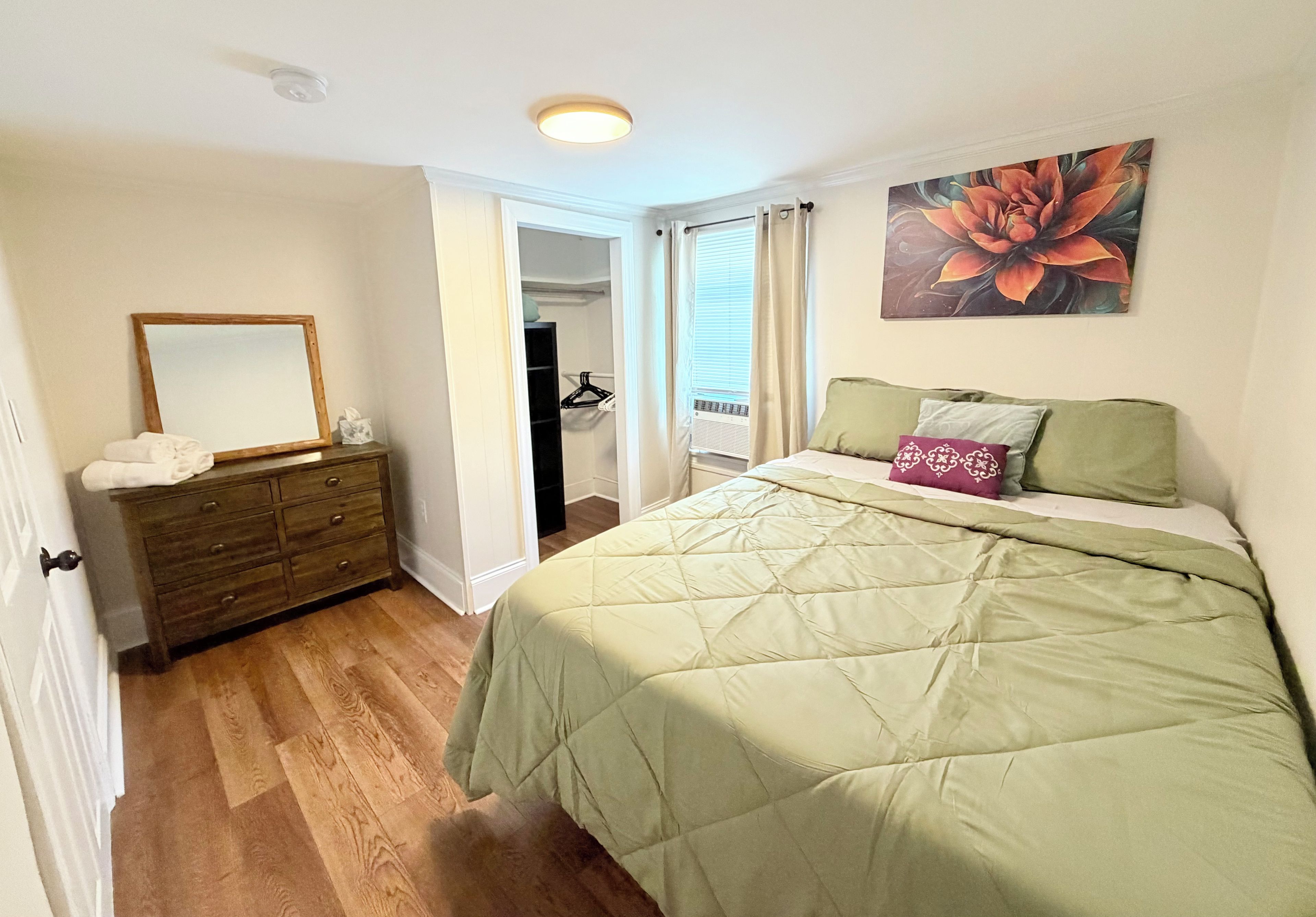 A bedroom with a bed, dresser, and a door leading to a closet.