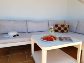 A white table with a plate of watermelon slices and a glass of water, a white sofa with cushions, and a patterned bag. - Relax, unwind and enjoy your own private villa in the Costa Papagayo area. (Playa Blanca)