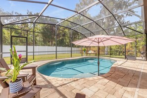 Une piscine extérieure couverte avec un espace patio comprenant des sièges et un pot de fleurs.