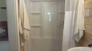 Un box de ducha con puerta de vidrio, un lavamanos blanco y un perchero para toallas.