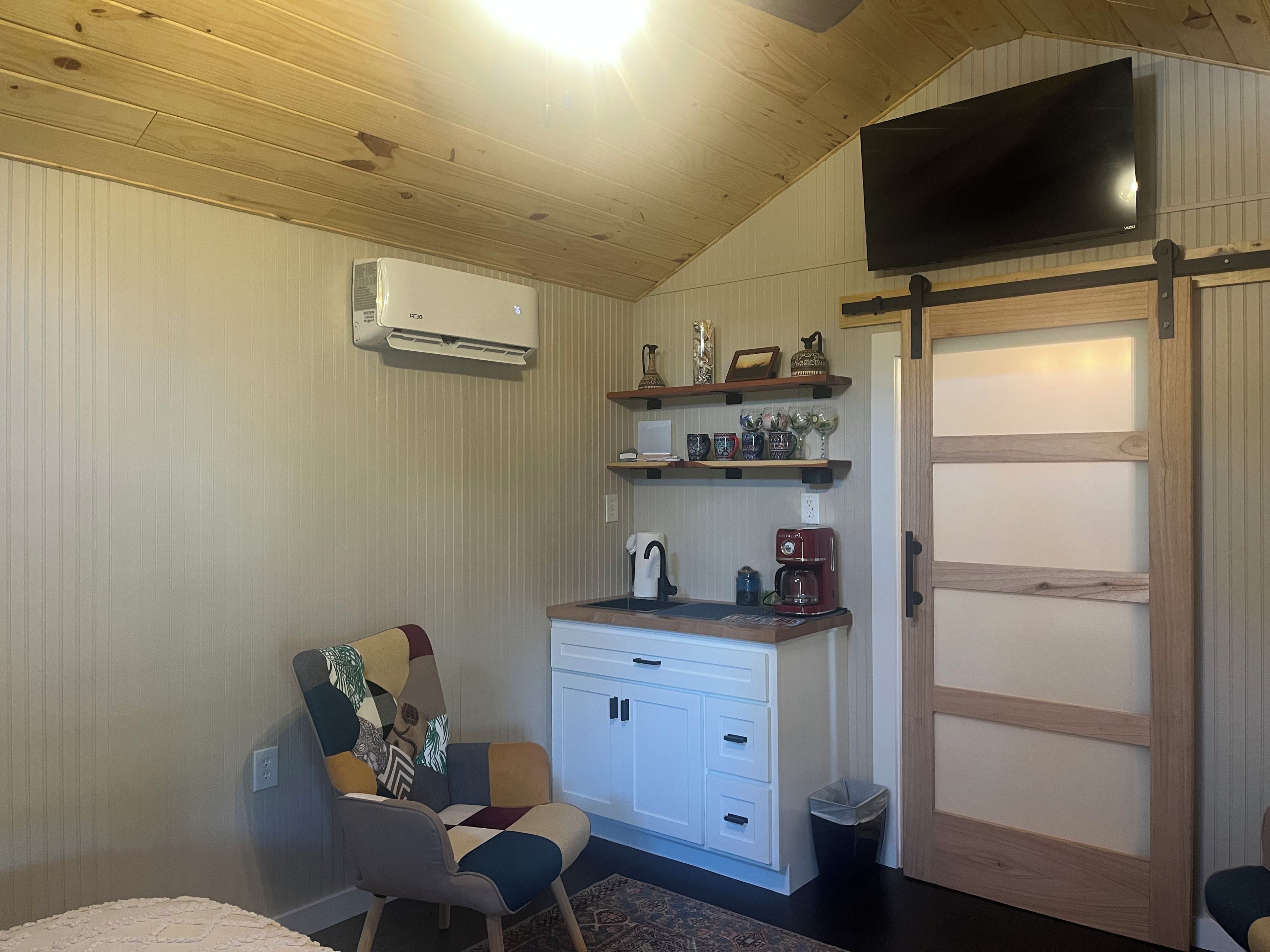 Kompakti keittiö, jossa on sisäänrakennettu liesi, valkoiset kaapit ja kahvinkeitin.
