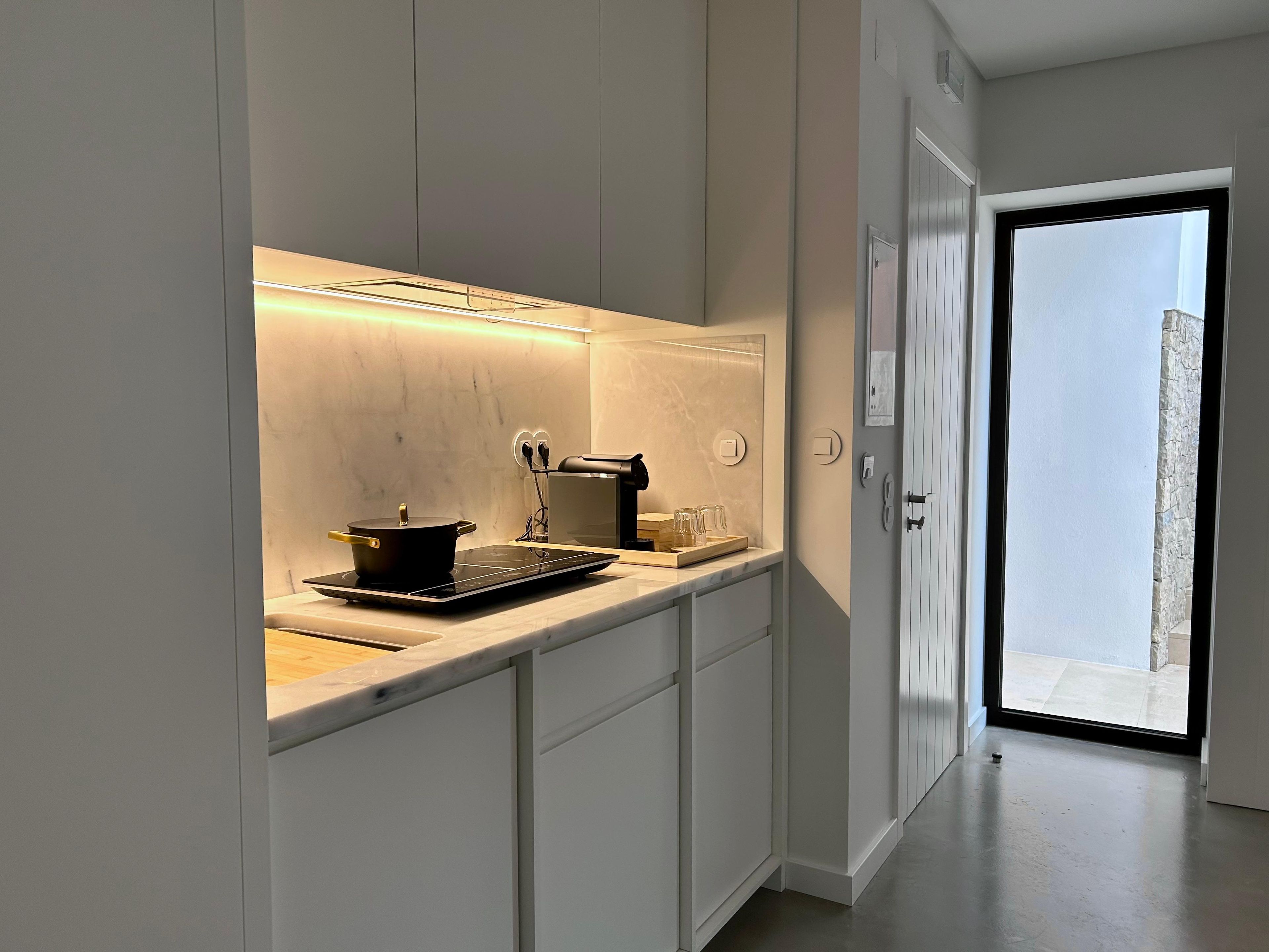Une cuisine moderne équipée d’une cuisinière intégrée, avec une casserole sur le plan de travail et une machine à café.