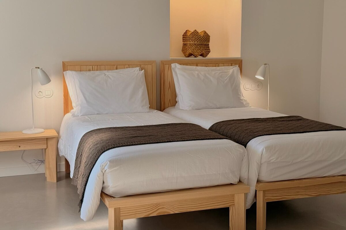 Ein Doppelbett mit Holz-Kopfteil, zwei Nachttische mit Lampen und eine Wandleuchte über dem Bett.