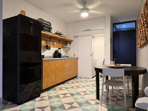 A compact kitchen with a black refrigerator, wooden cabinets, a countertop with kitchen appliances, and a dining table with chairs. - Moderno dpto. con Vistas y Terraza (Monterrey)