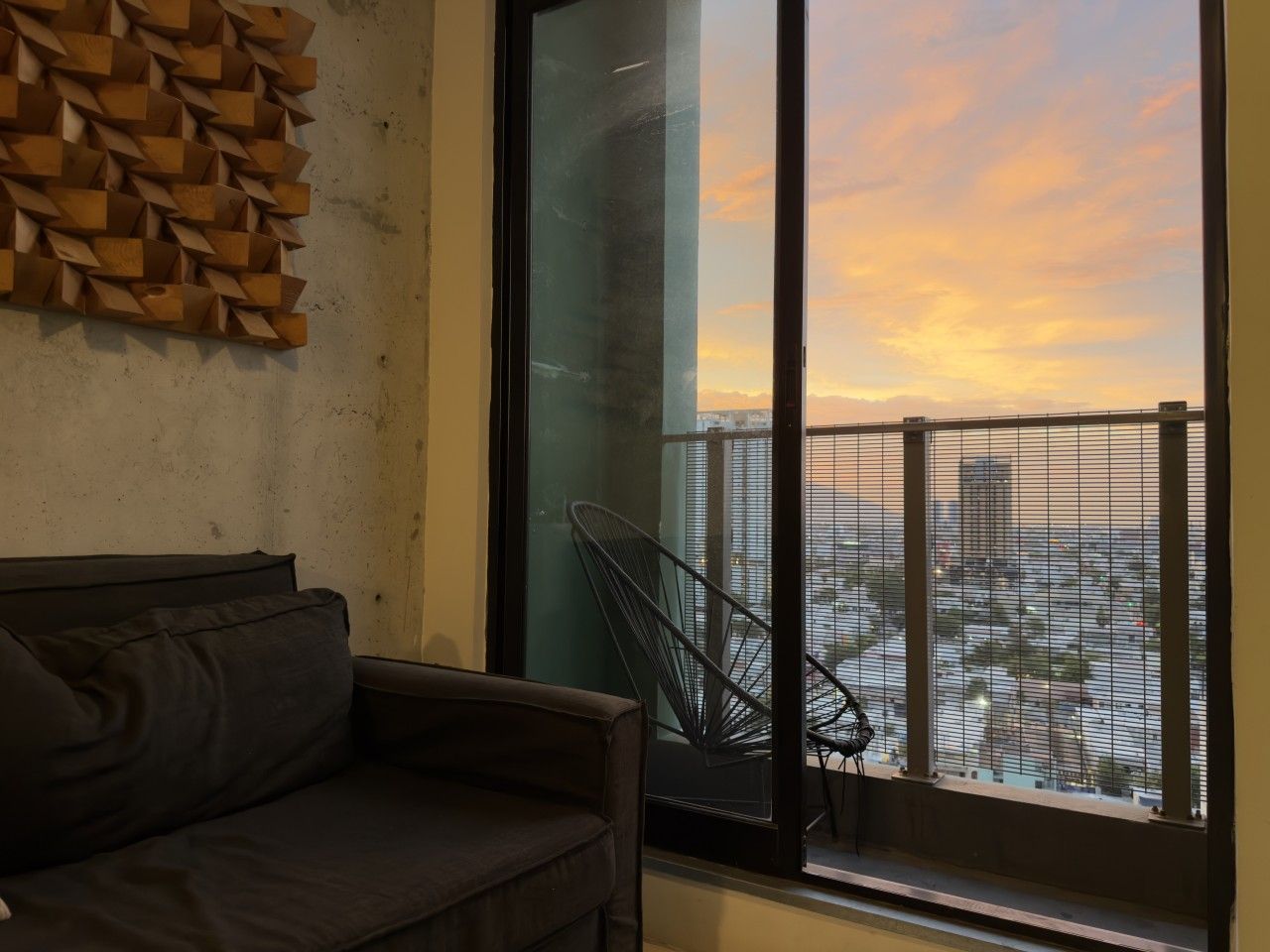 A modern living space with a sofa, a chair, and a large window with a city view.