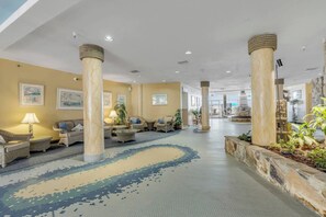 A hotel lobby with a central seating area, columns, and a patterned floor. - Oceanfront Resort Condo - Beach + Pool Views (Daytona Beach)