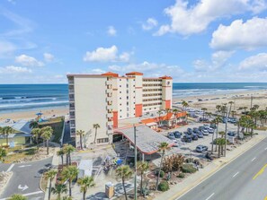Ein Hotel mit Blick auf den Strand, mehreren Etagen und einem Parkplatz.