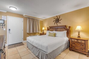 Ein Hotelzimmer mit einem Bett, Nachttischen, einer Wanduhr und einer Tür.