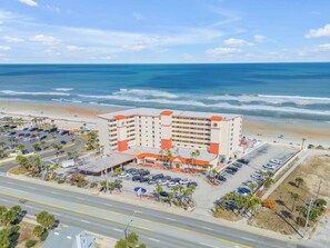 A multi-story hotel with a parking lot and beach view. - Oceanfront Resort Condo - Beach + Pool Views (Daytona Beach)